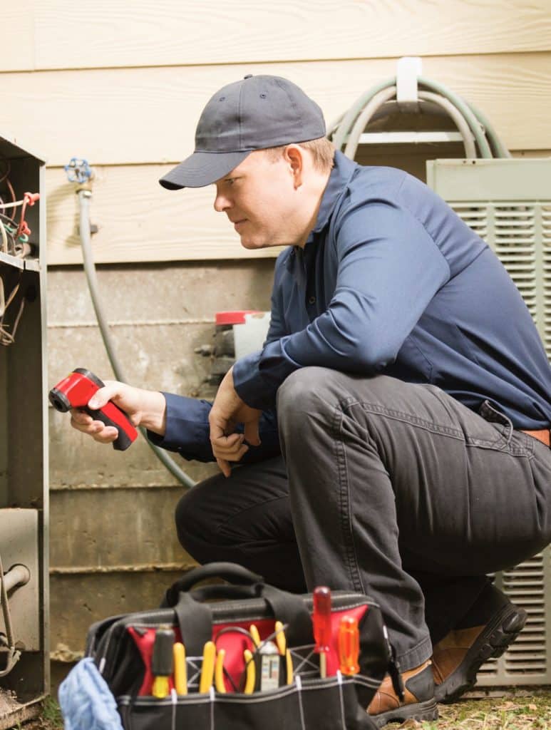 Air conditioner repairmen work on home unit. Blue collar workers.