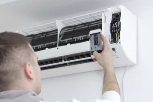 Electrician photographing an installation of air conditioners with smart phone.