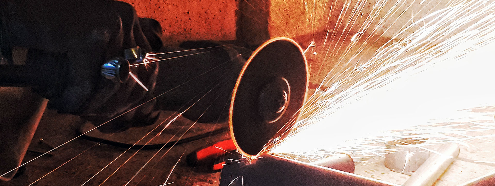 industrial metal worker grinding away at a steel beam