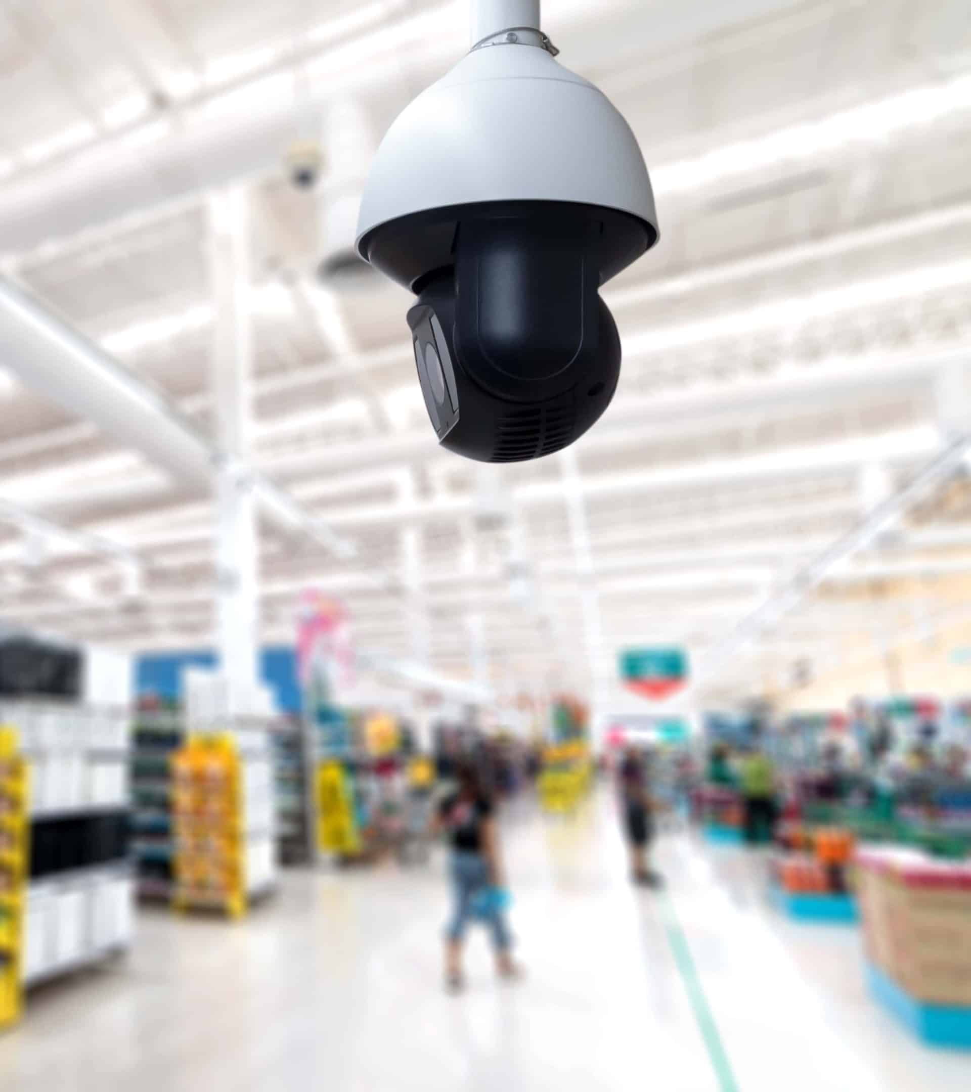 general store security camera featured in the foreground of a bustling store checkout area in the blurred background