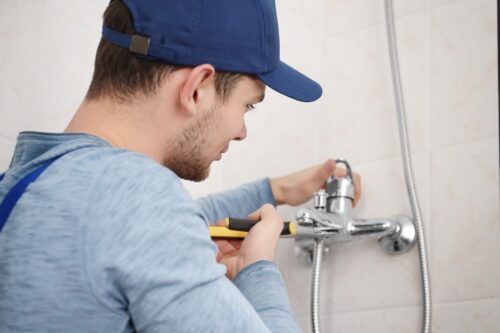 Plumber fixing faucet in bathroom