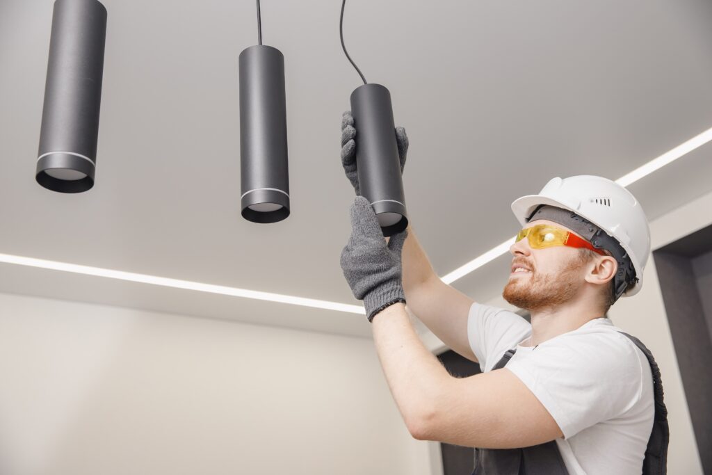 Electrician worker installation electric lamps light inside apartment. Construction decoration concept